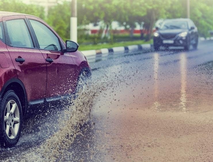 een rode auto die over een natte weg rijdt